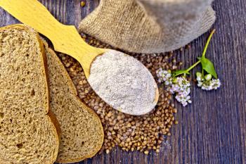 Buckwheat Flour in a wooden spoon, buckwheat in the bag, slices of bread, buckwheat flower on the background of wooden boards on top