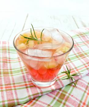 Lemonade with rhubarb and rosemary in a glass on a pink checkered napkin on a wooden boards background