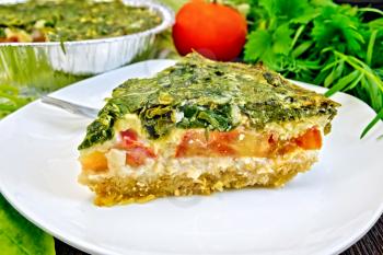 Celtic cake with spinach, tomatoes, oatmeal and eggs in a white plate in the form of baking foil, parsley on a wooden boards background