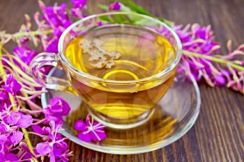 Herbal tea in a glass cup and fresh flowers fireweed against the backdrop of wooden planks