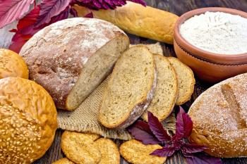 Bread, rolls and biscuits, amaranth flour in a clay bowl, purple amaranth flower on the background of wooden boards