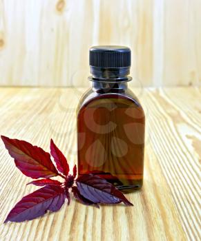 One vial of oil with branch burgundy amaranth on a wooden boards background