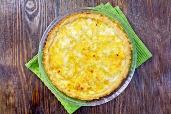 Tart with cheese, leek and sour and egg cream in a glass shape on a green kitchen towel on the background of wooden boards