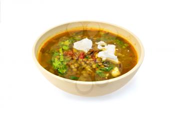 Lentil soup with spinach, tomatoes and feta cheese in a yellow dish isolated on white background