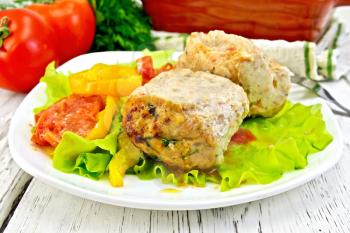 Cutlet of turkey meat with lettuce, tomato and pepper in a bowl, parsley, a towel and a fork on the background of wooden boards
