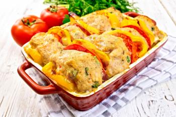 Cutlets of turkey meat baked with tomatoes and yellow pepper in a ceramic roasting pan on a towel, parsley on a wooden boards background