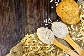 Flour and bran oat in spoon, oats stalks and oatmeal cookies on sacking on a background of wooden boards