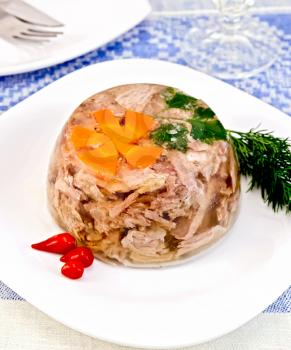 Jellied pork and beef with carrots and parsley on a plate with spicy red pertsemey and dill, mustard on a background of blue linen tablecloth