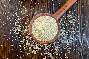 Sesame seeds in a clay ladle on a background of wooden boards on top