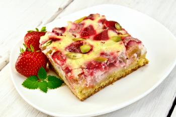 Piece of pie with strawberries, rhubarb and cream sauce, strawberry, mint in white plate on a wooden boards background