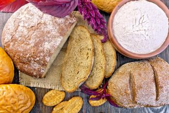 Bread, rolls and biscuits, flour of amaranth in a clay bowl, purple amaranth flower on the background of the wooden planks on top