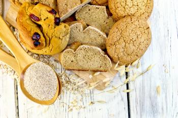 Bread, rolls and biscuits oat, bran in a spoonful, oat stalks on a background of wooden boards on top