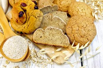 Bread, rolls and biscuits oat, bran in a spoonful, oat stalks on a background of wooden boards