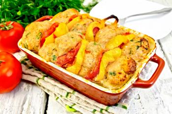 Cutlets of turkey meat baked with tomatoes and yellow pepper in a ceramic roasting pan on a kitchen towel, parsley on the background light wooden boards