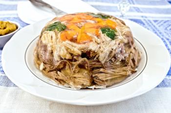 Jellied pork and beef with carrots and parsley on the plate on a mustard background of blue linen tablecloth