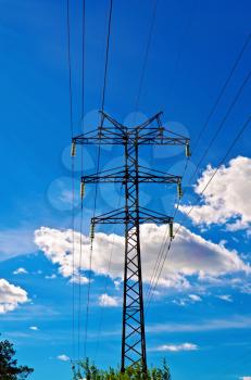 Pylon high-voltage power lines against the blue sky and white clouds