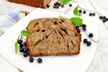 Two pieces of bird cherry fruitcake on the plate with a berries, napkin background wooden boards