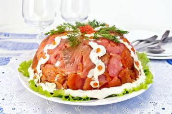Salad layered with salmon, egg, crab meat and rice, mayonnaise in a plate on a green lettuce on the background of a tablecloth