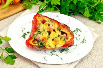 Sweet pepper stuffed with sausage, egg and cheese with dill in white plate on a napkin, parsley on a background of a granite table