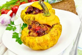 Two yellow squash stuffed with meat, tomatoes and peppers in the dish, bread, garlic, parsley and a napkin on a wooden boards background