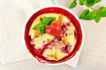 Strawberry pudding in a bowl with berries and mint on a napkin against the background of a granite table top