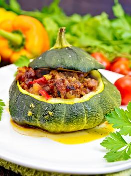 Squash green stuffed with meat, tomatoes and peppers on a napkin, garlic and parsley on a dark wooden board