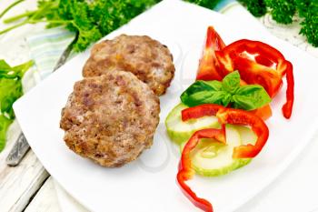 Cutlets stuffed with spinach and egg, salad with tomatoes, cucumber and pepper in a dish, basil and parsley on a wooden board background