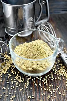 Hemp Flour in a glass cup, blender, sieve and cookie cutters on a dark wooden board