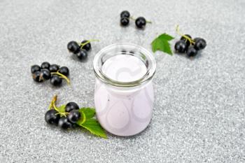 Milk cocktail with black currant in a glass jar with berries on the background of a stone table