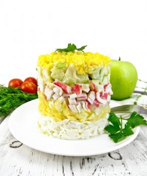 Salad of crab meat, cheese, eggs and green apple in the plate, napkin, background dill on a wooden board