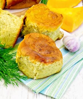 Pumpkin Scones with garlic and dill on a green towel, yellow pumpkin slices on the background light wooden boards