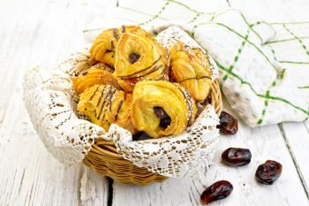 Cookies with dates in a wicker basket with a napkin, fruit and towel on a background of wooden boards