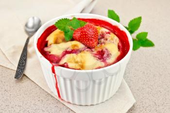 Pudding strawberry in tall white bowl with berries and mint on a napkin on a background granite table