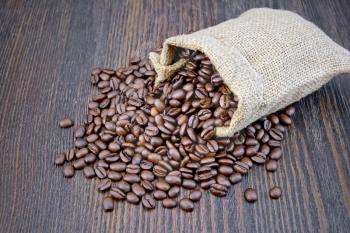 A bag of black coffee beans on a background of a dark wooden board