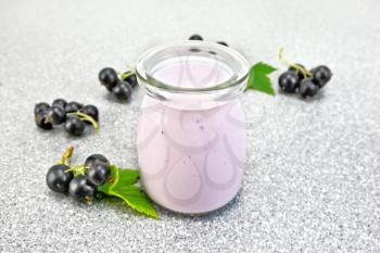 Milk cocktail with black currant in a glass jar with berries on the background of a gray stone table