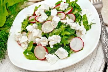 Salad with spinach, cucumbers, radish and salted cheese, dill and green onions in a white plate, a towel on the background of a light wooden board