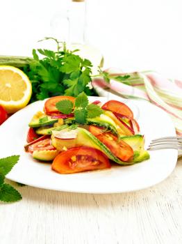 Salad from young zucchini, radish, tomato and mint flavored with lemon juice and soy sauce in a white plate, napkin on a wooden board background