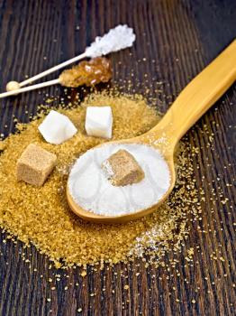 Sugar white and brown in cubes, granulated in a spoon and crystal on a stick against the background of a wooden board