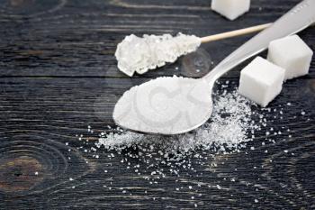 Sugar white granulated in a spoon, crystal and cubes on the background of a black wooden board