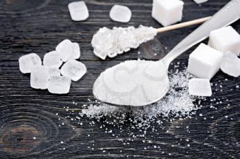 Sugar white granulated in a spoon, crystal and cubes on a wooden plank background