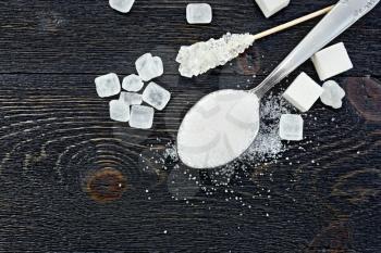 Sugar white granulated in a spoon, crystal and cubes on the background of a wooden board from above