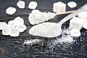 Sugar white granulated in a metal spoon, crystal and cubes on a wooden plank background