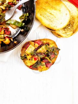 Toasted slice of bread with stewed chard, onion and orange on a wooden plank background on top