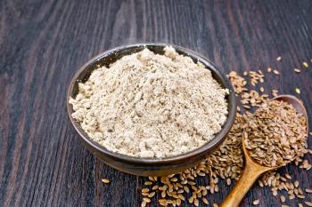 Flax flour in a bowl, seeds in a spoon and on a table on the background of a wooden board