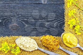 Frame of seeds and flowers of mustard, mustard and granular sauce, powder in spoons on the background of a black wooden board