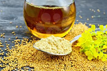 Mustard powder in a spoon, oil in a glass jar, seeds and flower mustard on a wooden board background