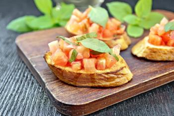 Bruschetta with tomatoes and basil on a dark wooden table background
