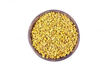 Fenugreek seeds in a clay bowl isolated on white background from above