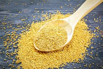 Mustard seeds in a spoon on the background of a wooden board
