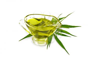 Hemp oil in a glass sauceboat, cannabis leaves and stalks  isolated on white background
